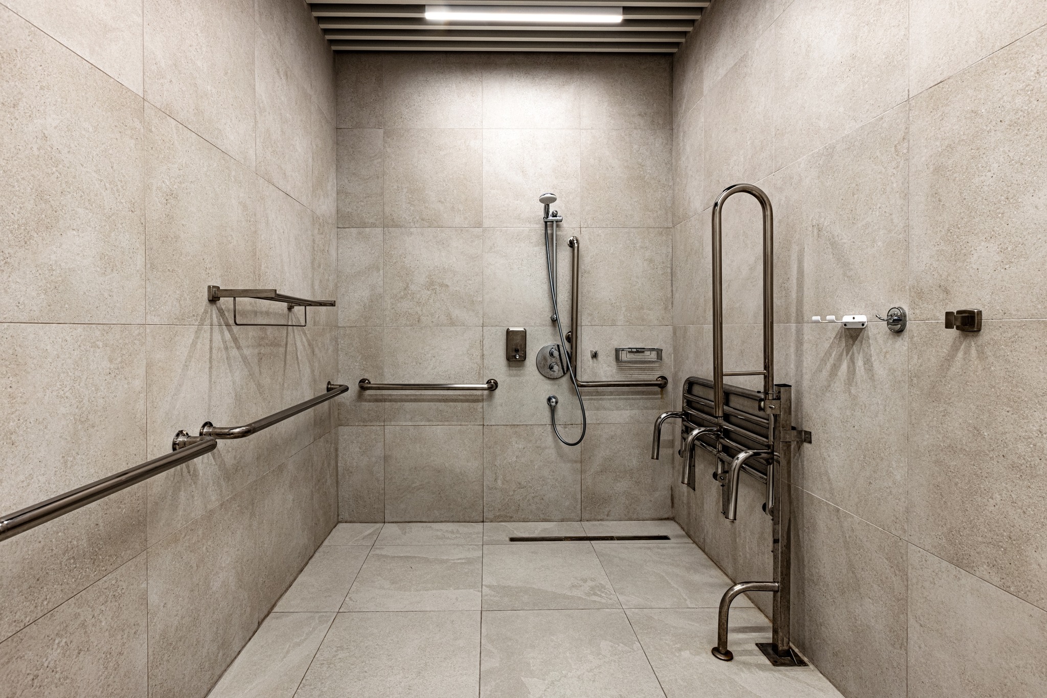 Accessible shower with safety grab bars and foldable seat in modern bathroom.