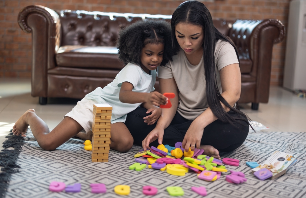 A child playing with letters with their mom.