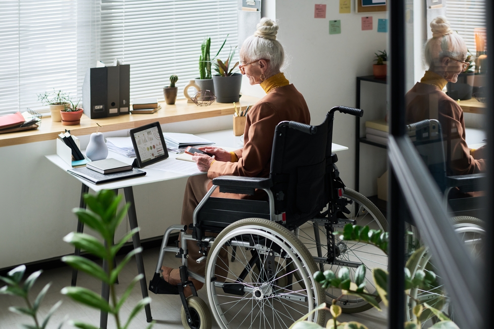 A senior woman in a wheelchair working in her home office.