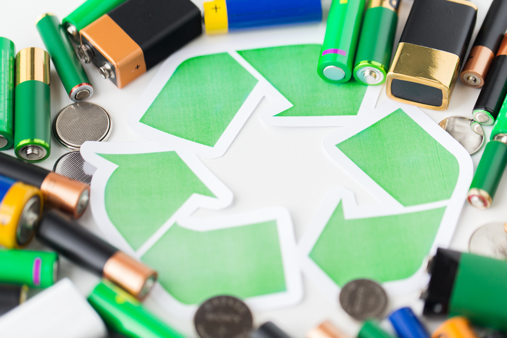 An image of a recycling symbol surrounded by various kinds of batteries.