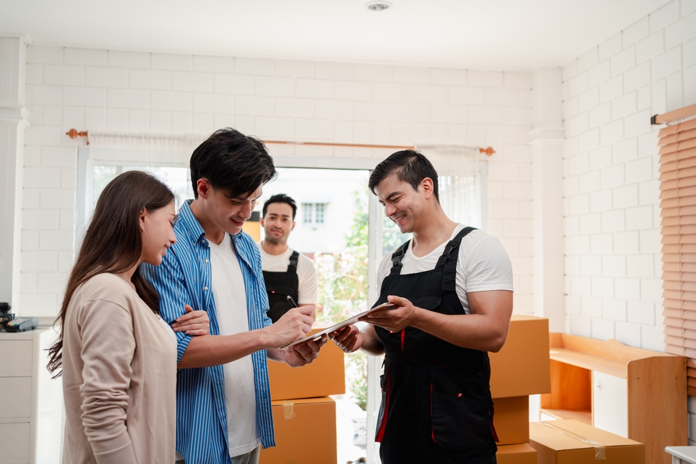 A couple signing off on a cliff board with professional movers.