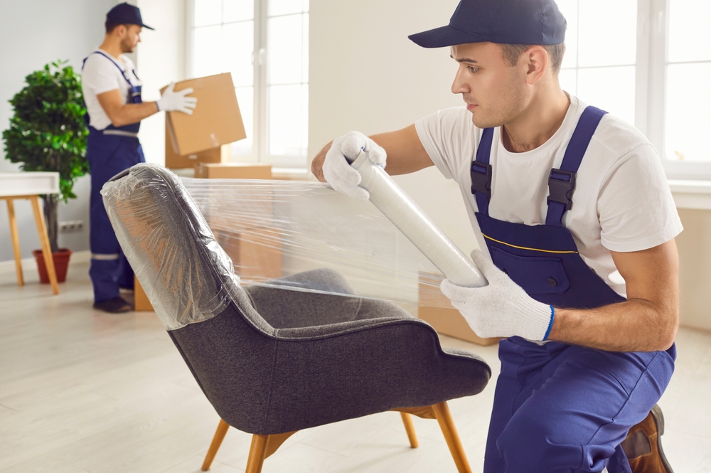 A professional mover wrapping a chair in protective film.