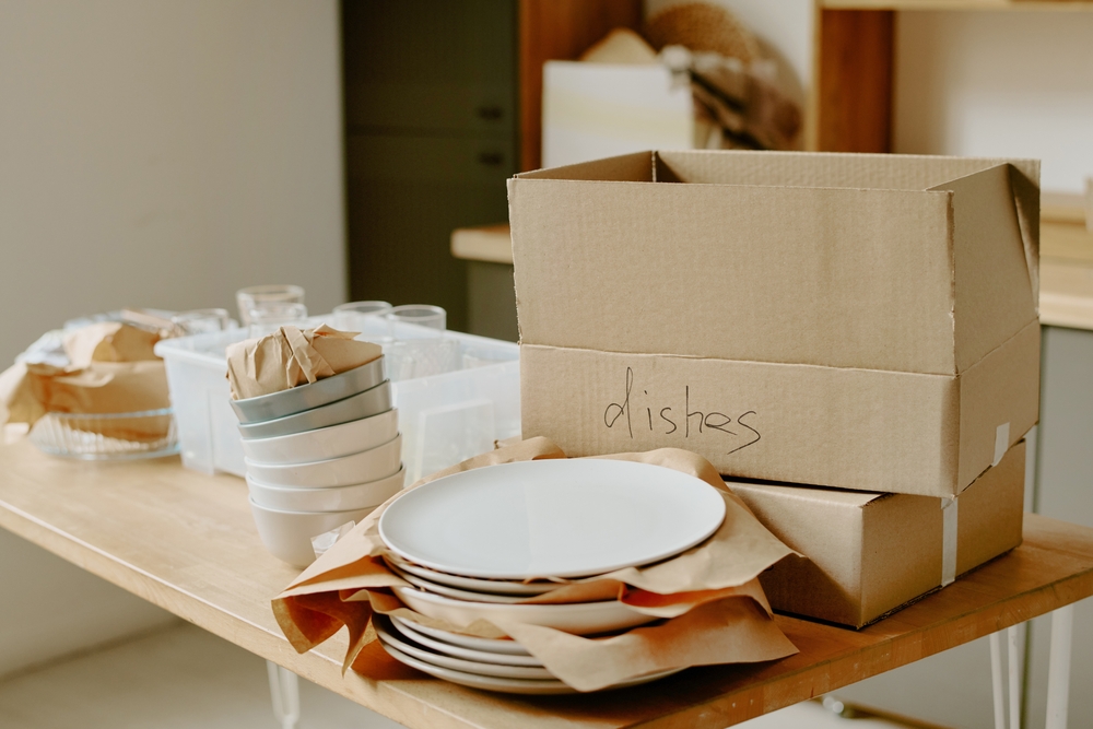 Dishes and other kitchen items on a table ready to be packed.