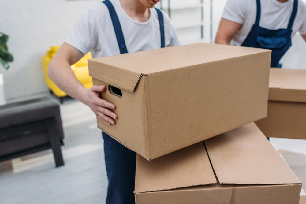 An image of professional movers stacking boxes in a living room.