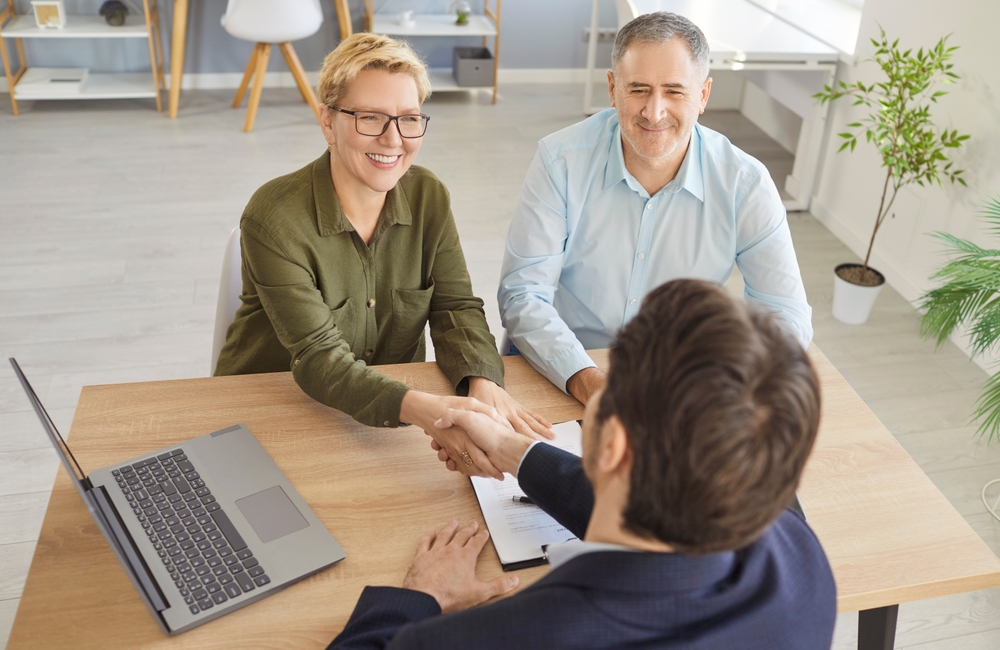 A senior couple shaking hands with a realtor.