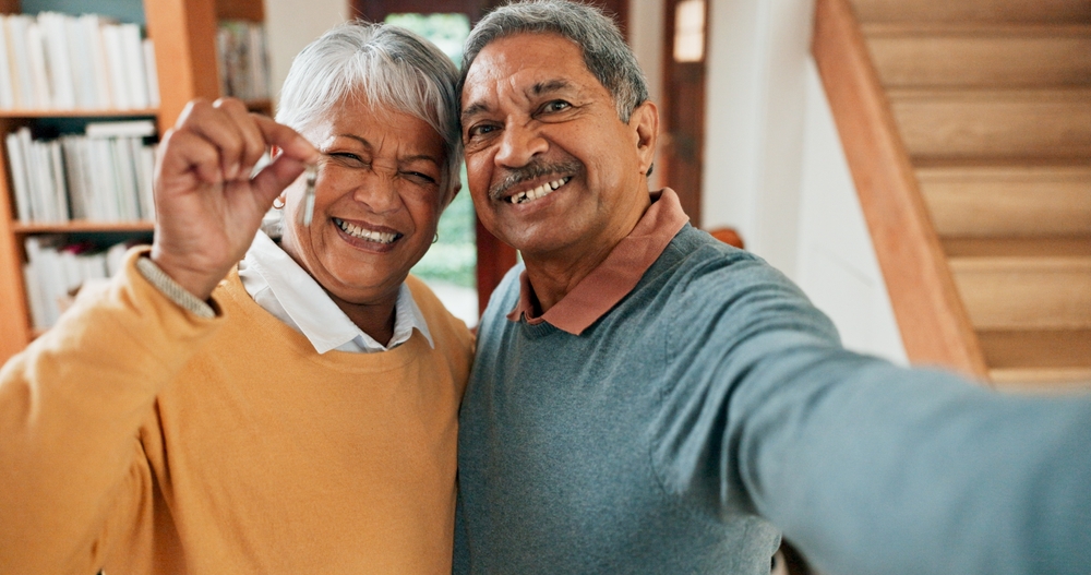 A selfie of a senior couple holding house keys.