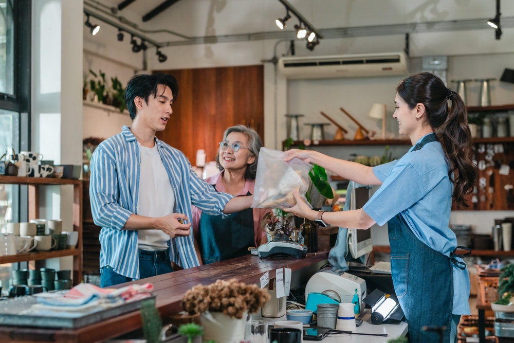 A small business ceramic shop, where a cashier is handing a customer an item.