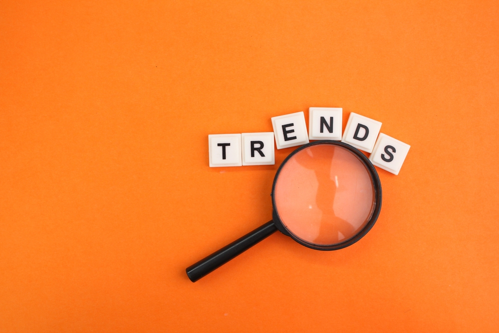 An image of a magnifying glass on an orange background with 'trends' spelled out in block letters.