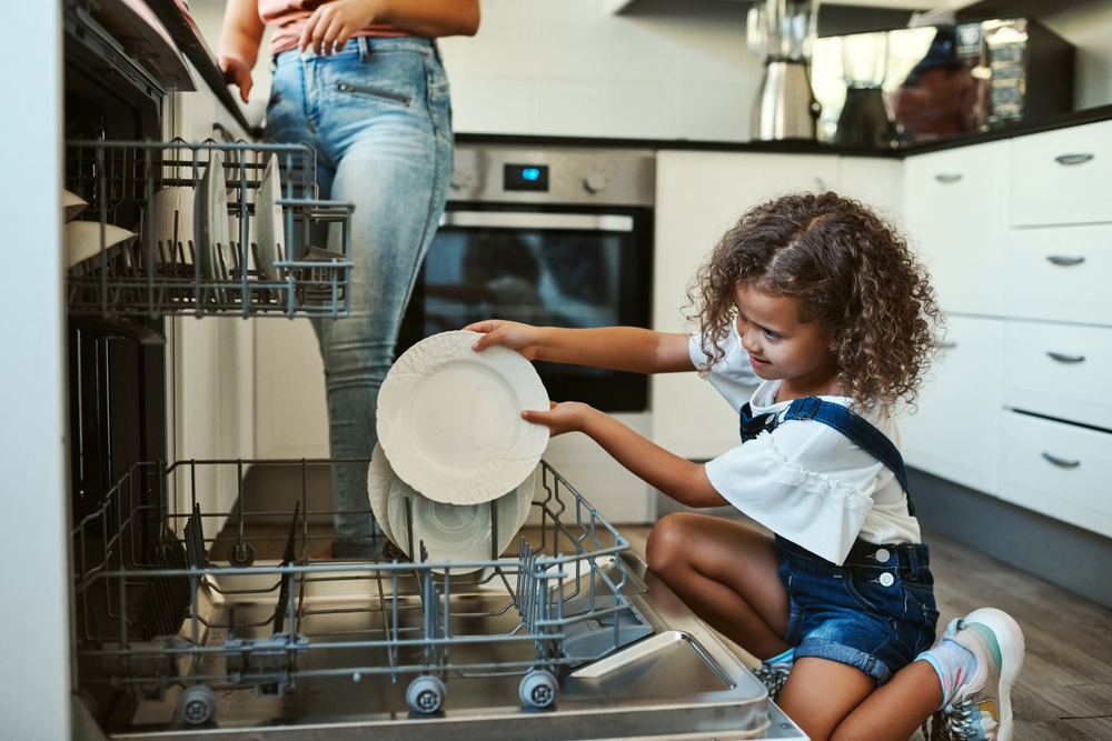 A child helping to load a dishwasher.