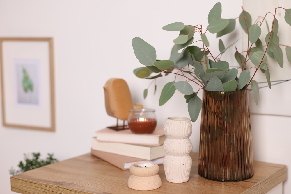 An image of a clean desk decorated with modern decor, including a vase of plants and a stack of books.
