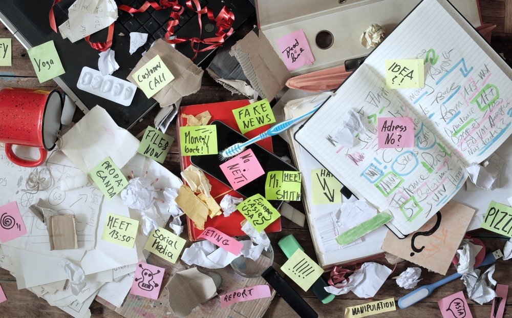 An image of a messy office workplace with post it notes and papers.