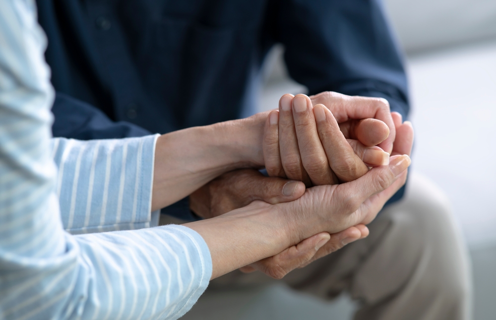 A closeup image of two seniors holding hands.