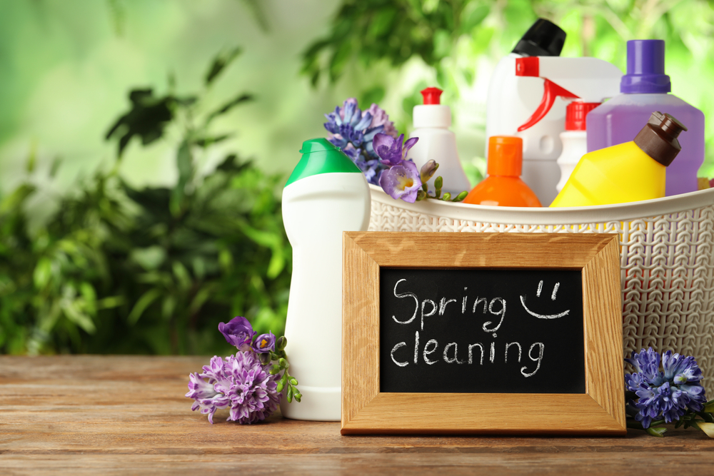 A sign reading: 'Spring Cleaning' in front of a basket of cleaning supplies.