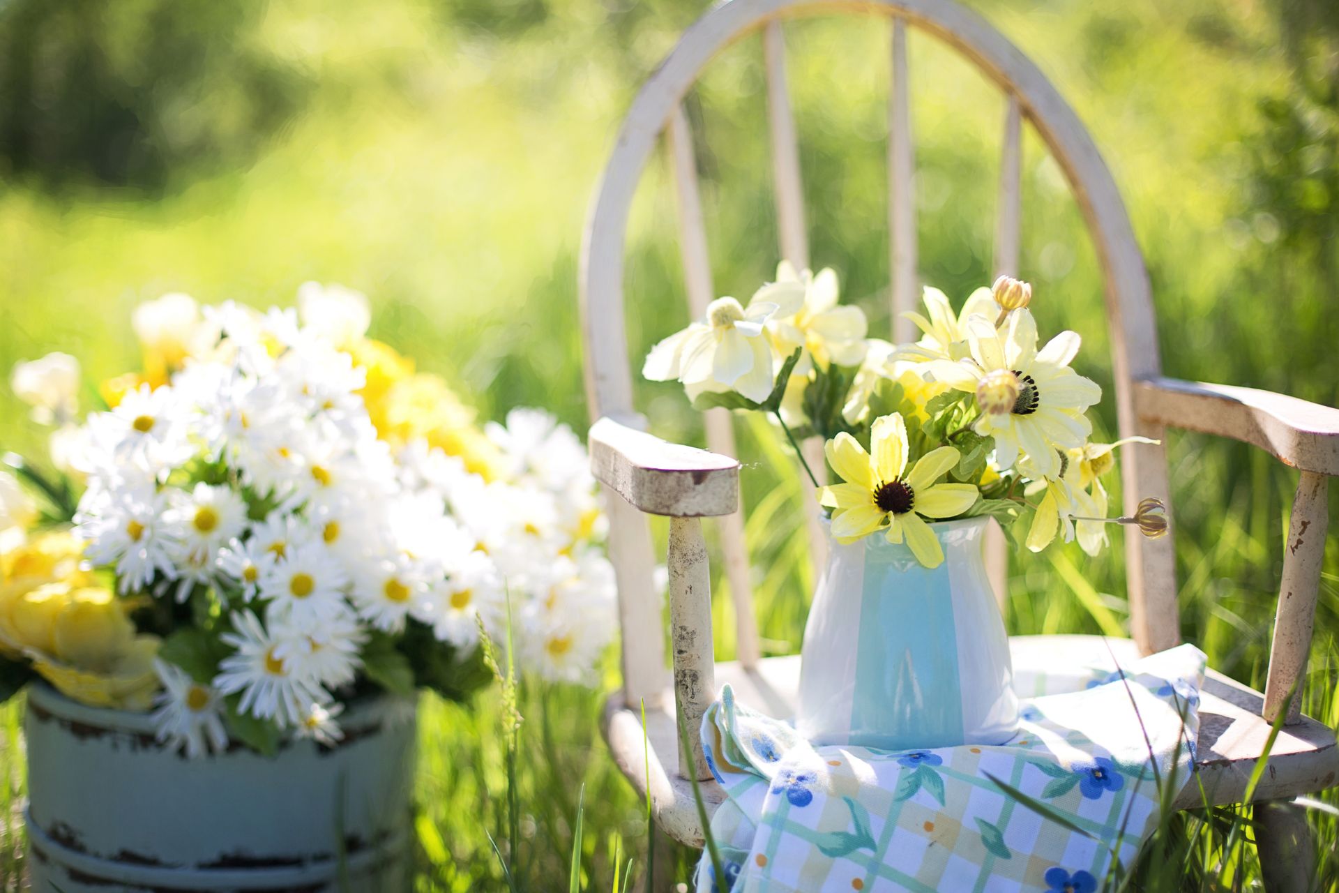 An image of a set of flowers on a rocking chair outdoors.