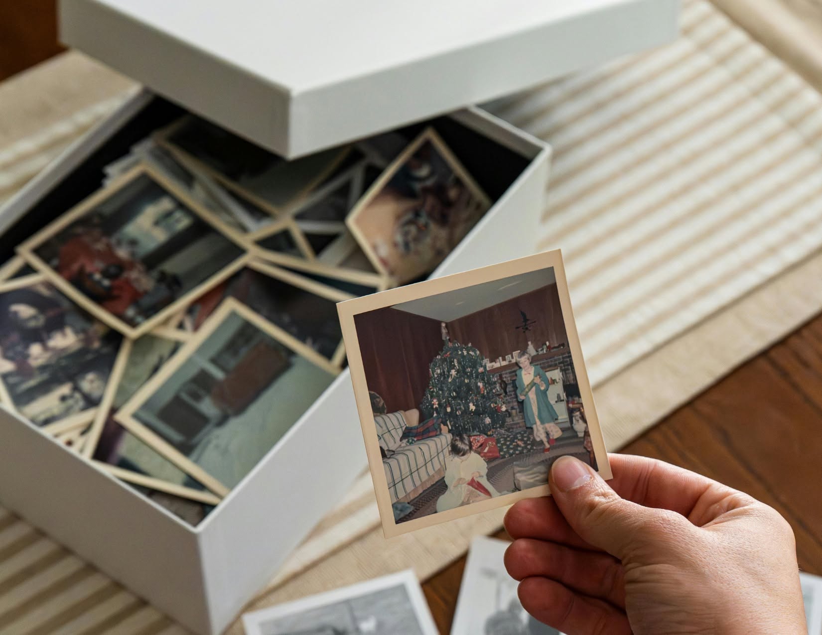 An image of a person's hands looking through photos from a photo storage box.