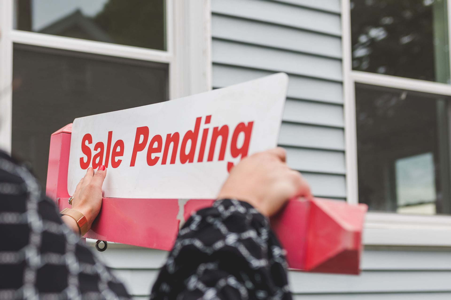 An image of a 'Sale Pending' sign outside of a house.